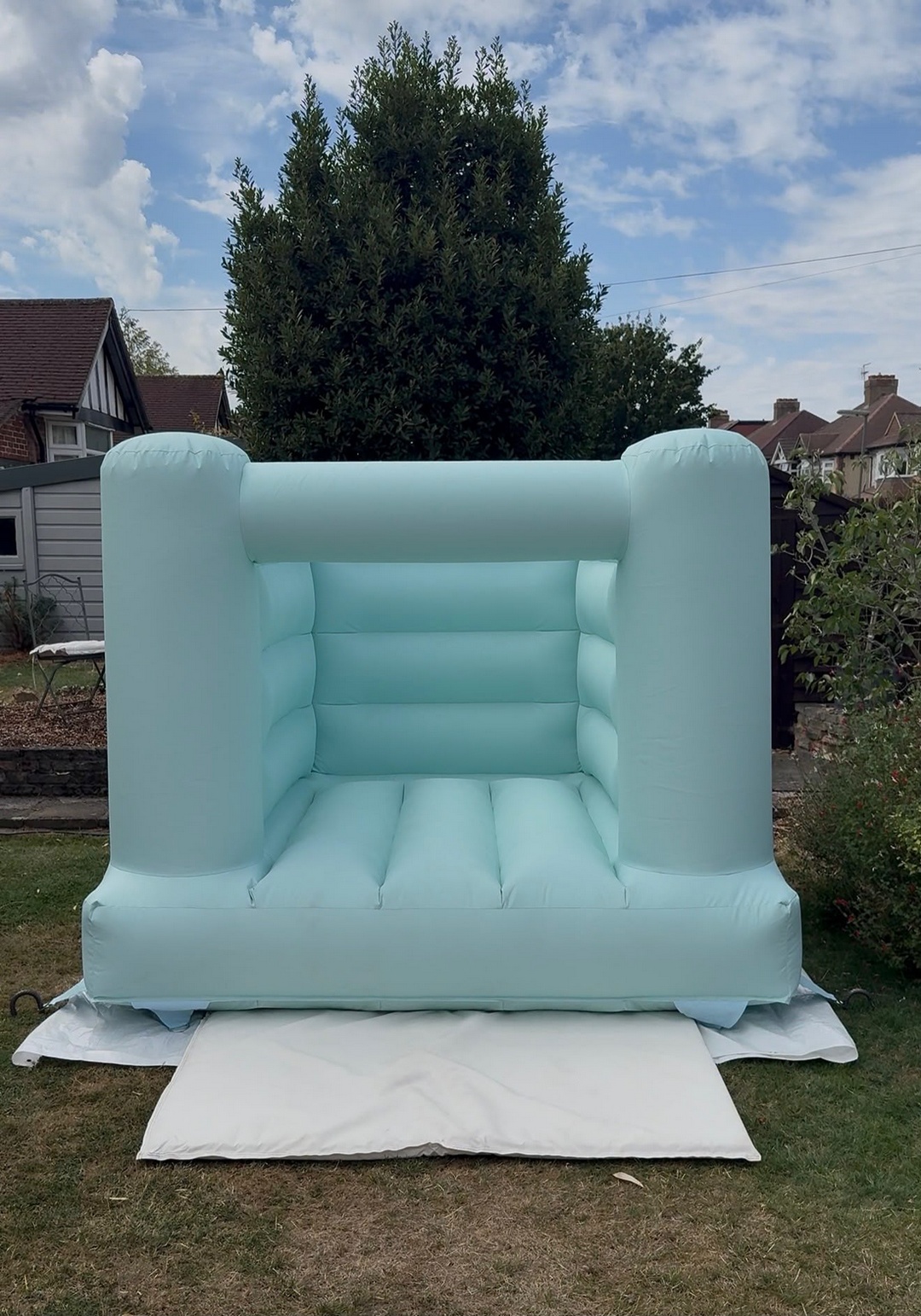 Blue mint bouncy castle set up on a garden lawn