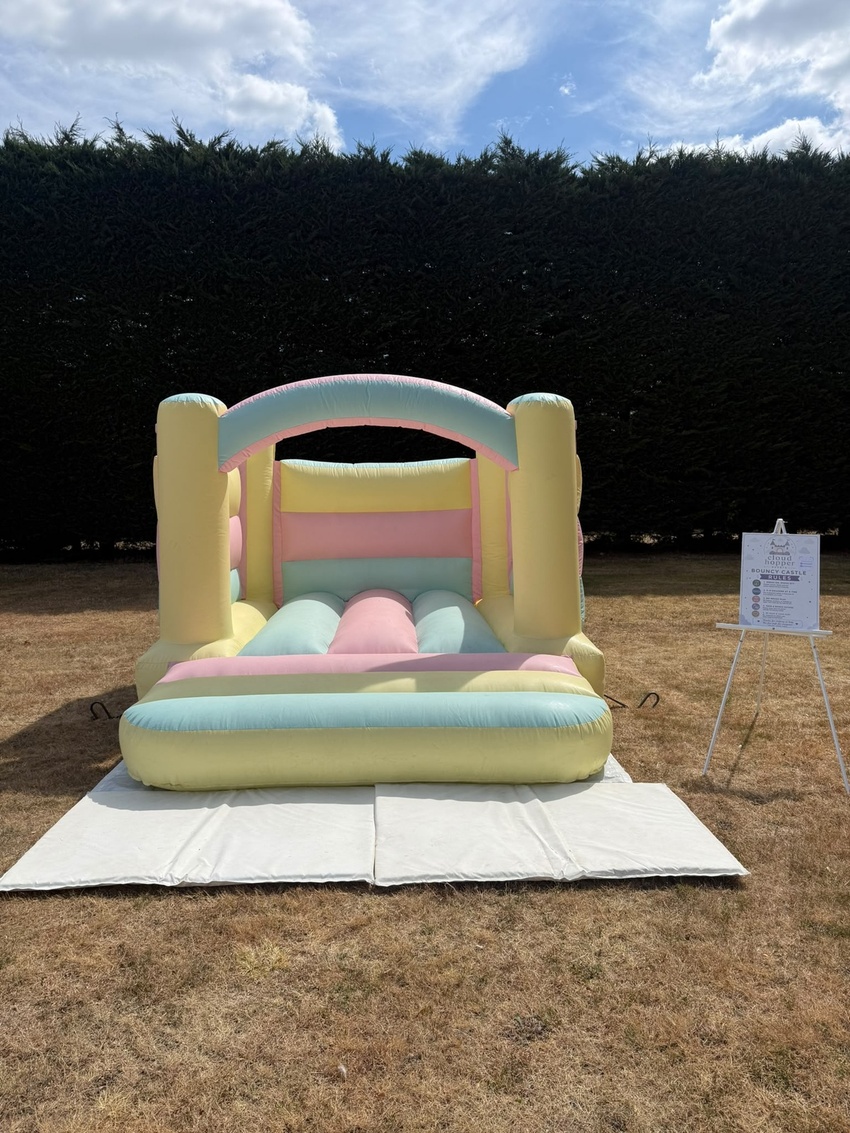 Pastel rainbow bouncy castle on a lawn